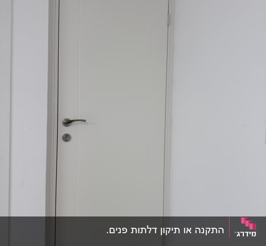 דלת לבנה עם ידית כסופה בקיר לבן